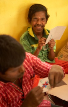 Papermaking has its own division of the Families For Children Training Center. Some residents tear the newspaper to make the recycled paper. Others, like these young men are responsible for embroidering designs on the cards.